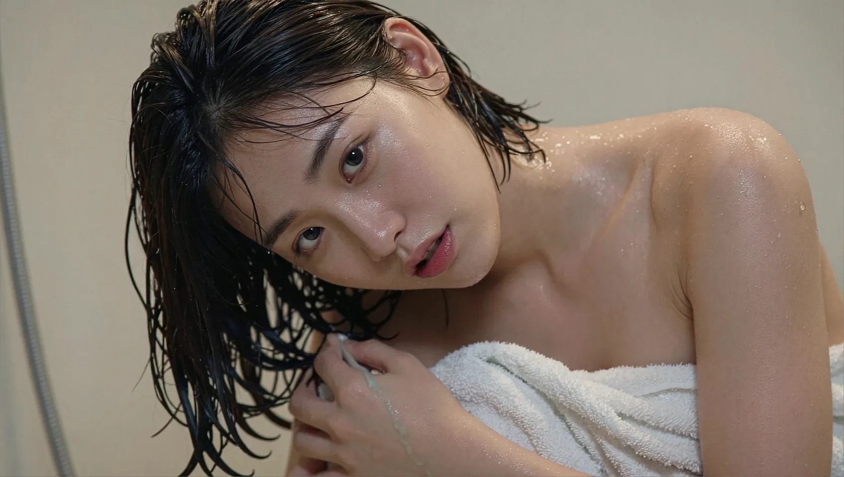 Fictional AI character with wet hair holding a white towel in soft light